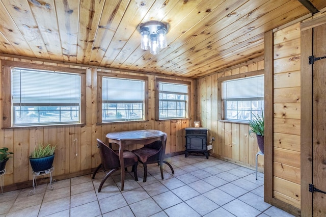 interior space with wooden ceiling, wood walls, and a wood stove