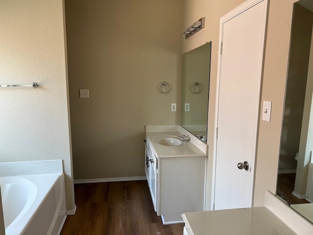 bathroom with a washtub, wood-type flooring, and vanity