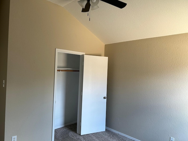 unfurnished bedroom with a closet, ceiling fan, vaulted ceiling, and dark colored carpet