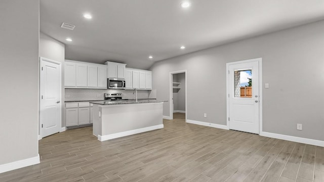 kitchen featuring a center island with sink, appliances with stainless steel finishes, light hardwood / wood-style flooring, and white cabinetry