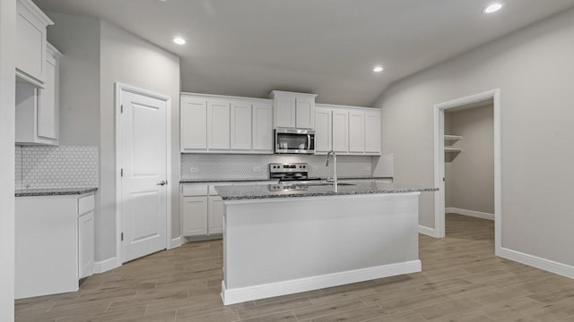 kitchen with white cabinets, appliances with stainless steel finishes, and a kitchen island with sink