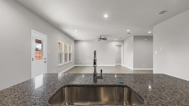 kitchen featuring sink, ceiling fan, and dark stone counters