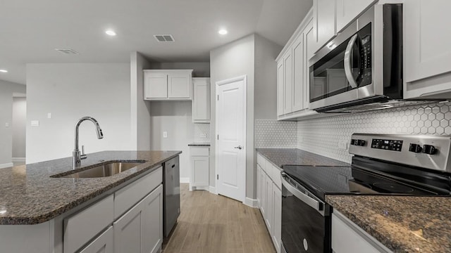 kitchen featuring an island with sink, appliances with stainless steel finishes, white cabinetry, and sink