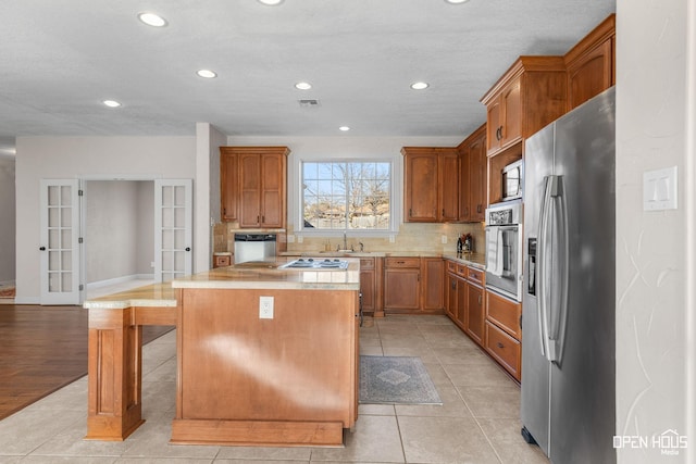 kitchen with french doors, light tile patterned flooring, a breakfast bar area, a kitchen island, and appliances with stainless steel finishes