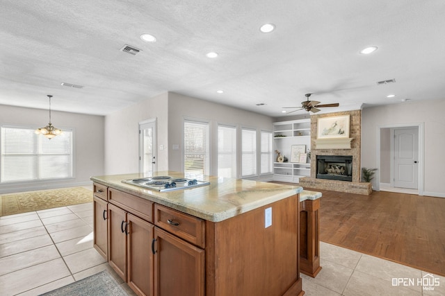 kitchen featuring a textured ceiling, a large fireplace, light tile patterned floors, a healthy amount of sunlight, and pendant lighting