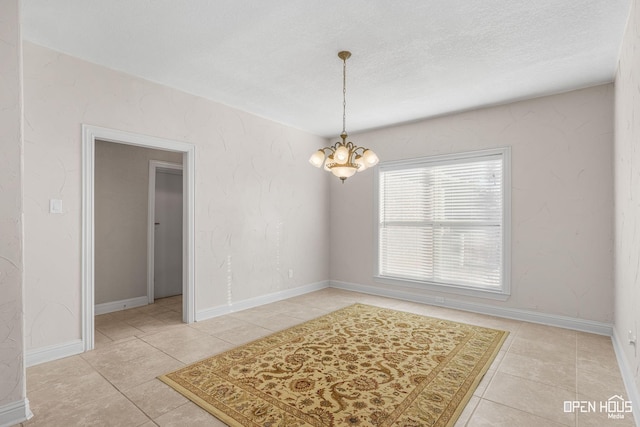 empty room featuring a notable chandelier and light tile patterned flooring