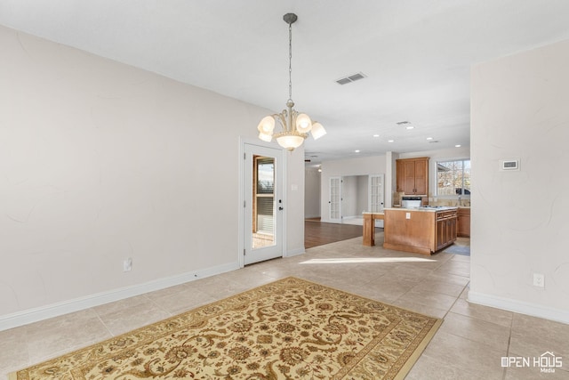 unfurnished dining area with an inviting chandelier and light tile patterned floors