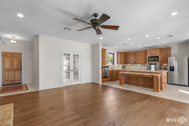 kitchen with a center island, stainless steel appliances, french doors, light wood-type flooring, and ceiling fan