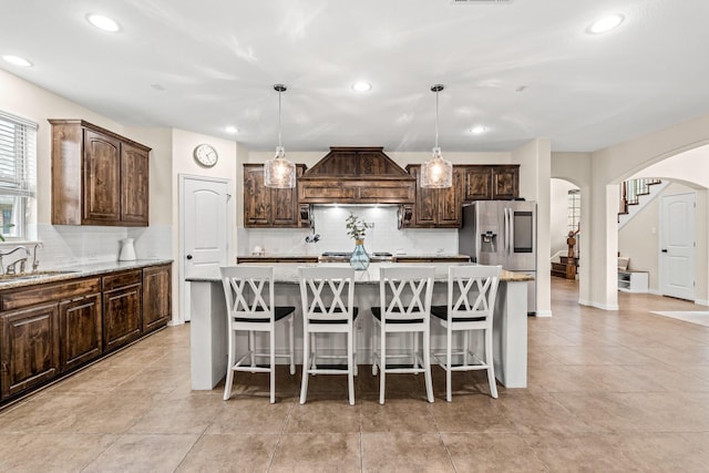 kitchen featuring sink, a kitchen island, decorative light fixtures, and premium range hood