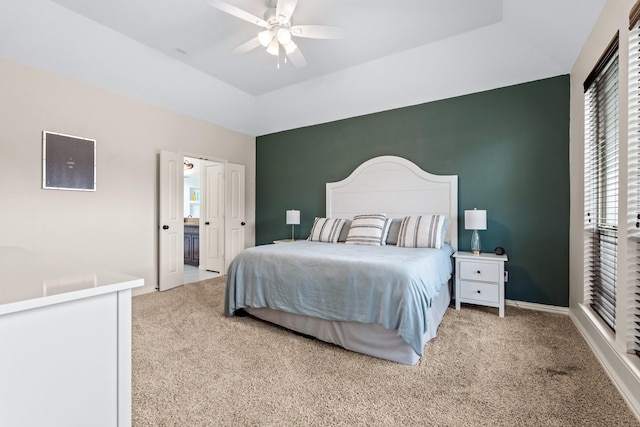 carpeted bedroom with a raised ceiling and ceiling fan