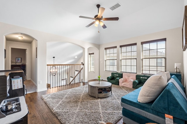 living room featuring lofted ceiling, ceiling fan with notable chandelier, plenty of natural light, and dark wood-type flooring