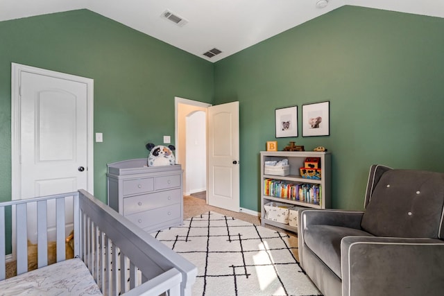 carpeted bedroom with a crib and lofted ceiling