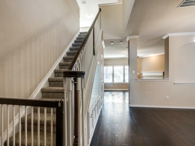 stairs featuring wood-type flooring and crown molding