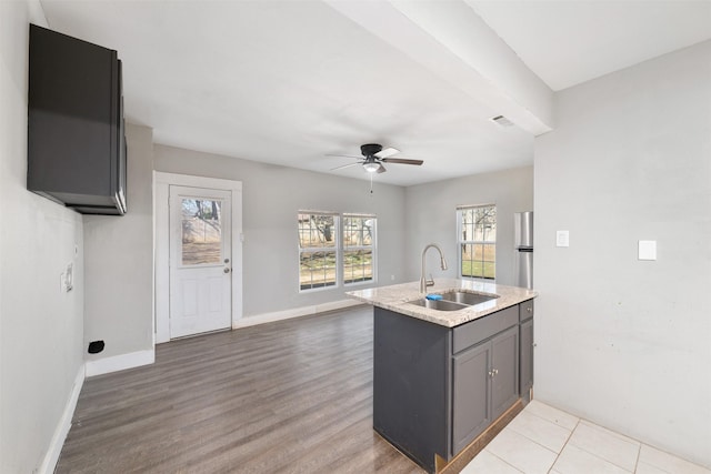 kitchen with sink, ceiling fan, plenty of natural light, and light stone counters