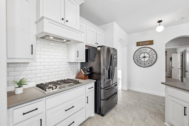 kitchen with stainless steel appliances, white cabinets, light tile patterned flooring, tasteful backsplash, and premium range hood