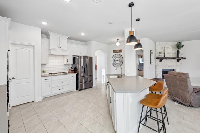 kitchen with sink, white cabinetry, an island with sink, backsplash, and appliances with stainless steel finishes