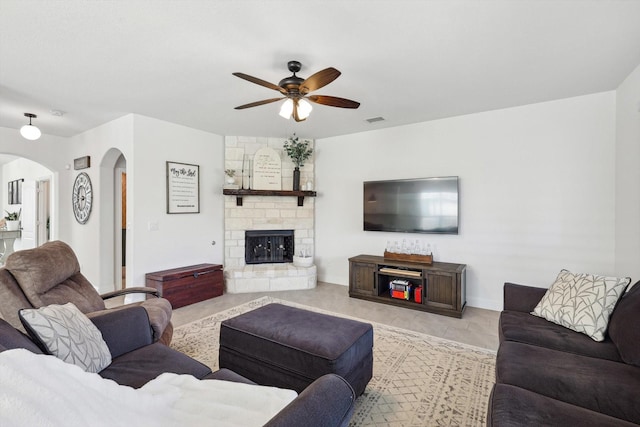 living room with ceiling fan and a stone fireplace