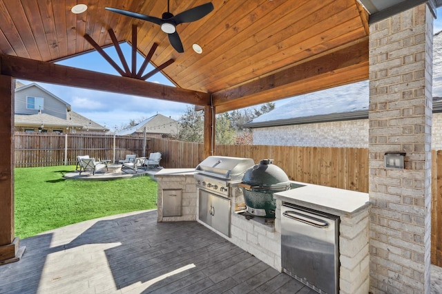 view of patio featuring an outdoor fire pit, a grill, a wooden deck, exterior bar, and exterior kitchen