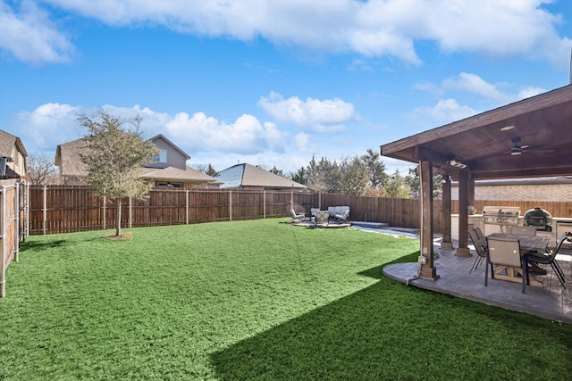 view of yard featuring ceiling fan, an outdoor kitchen, and a patio area