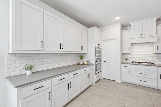 kitchen with stainless steel appliances, white cabinetry, tasteful backsplash, and light tile patterned floors