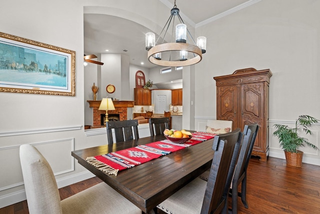 dining area with a chandelier, a brick fireplace, dark hardwood / wood-style flooring, and ornamental molding