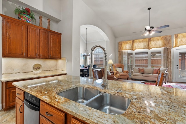 kitchen featuring backsplash, vaulted ceiling, sink, light stone counters, and ceiling fan with notable chandelier