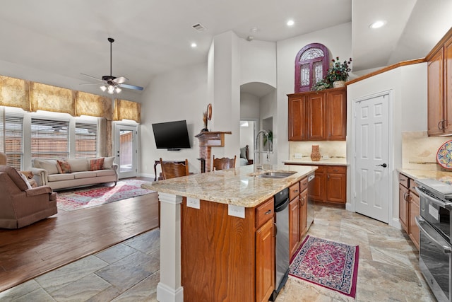 kitchen featuring sink, backsplash, double oven range, a kitchen island with sink, and ceiling fan