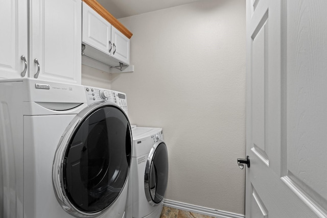 clothes washing area with cabinets and washer and dryer