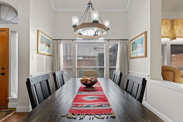 dining area with dark wood-type flooring, ornamental molding, and a chandelier