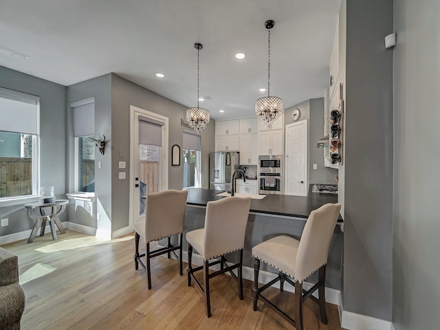 kitchen with stainless steel appliances, white cabinetry, an inviting chandelier, pendant lighting, and a breakfast bar