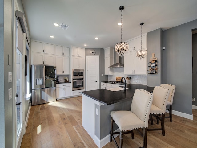 kitchen featuring stainless steel appliances, decorative light fixtures, white cabinets, a kitchen breakfast bar, and a chandelier