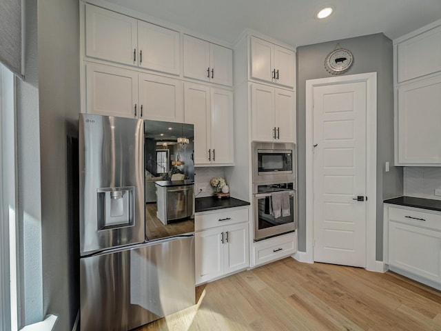 kitchen featuring stainless steel appliances, white cabinets, and decorative backsplash