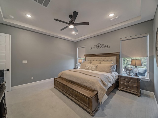 bedroom featuring ceiling fan, light carpet, and a raised ceiling