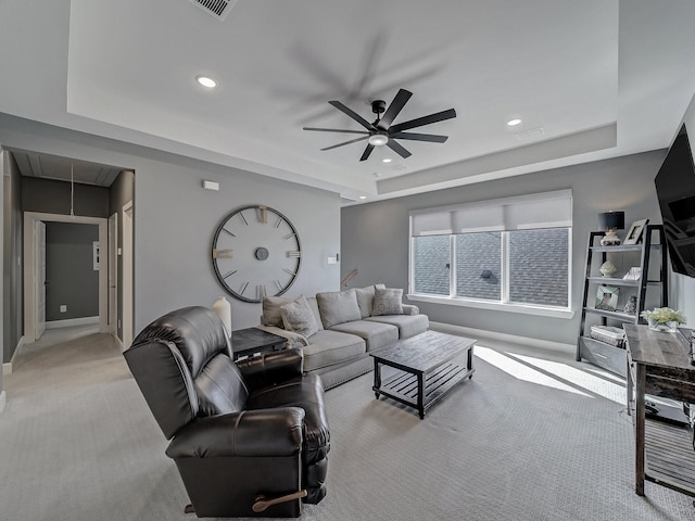 living room featuring light carpet, ceiling fan, and a tray ceiling