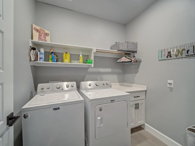 laundry area with washing machine and dryer, light tile patterned floors, and cabinets