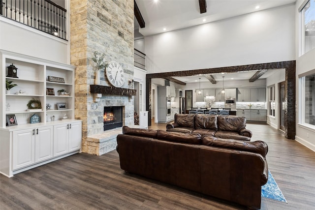 living room featuring a towering ceiling, a fireplace, beamed ceiling, and dark hardwood / wood-style floors