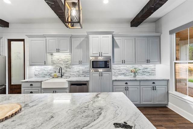 kitchen featuring sink, beamed ceiling, light stone countertops, dark hardwood / wood-style flooring, and appliances with stainless steel finishes