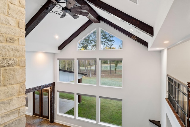 unfurnished living room with hardwood / wood-style flooring, high vaulted ceiling, beam ceiling, and a healthy amount of sunlight