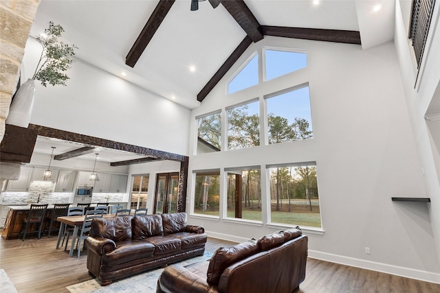 living room with high vaulted ceiling, wood-type flooring, ceiling fan, and beam ceiling