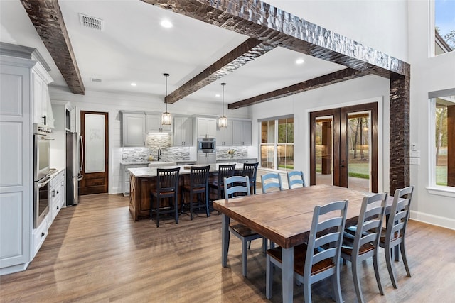 dining space featuring sink, dark hardwood / wood-style floors, and beam ceiling