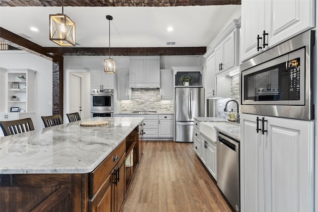 kitchen with a kitchen island, stainless steel appliances, backsplash, and white cabinetry