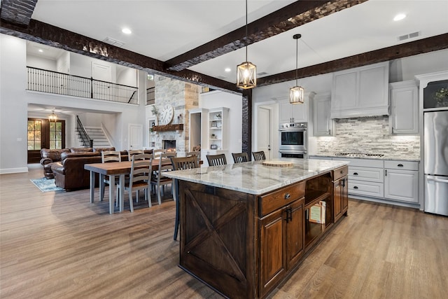 kitchen featuring white cabinets, a kitchen bar, a center island, and a fireplace