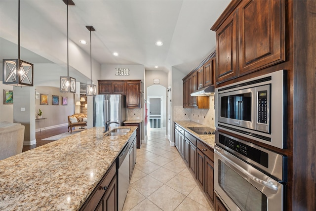 kitchen featuring light stone counters, appliances with stainless steel finishes, backsplash, and pendant lighting