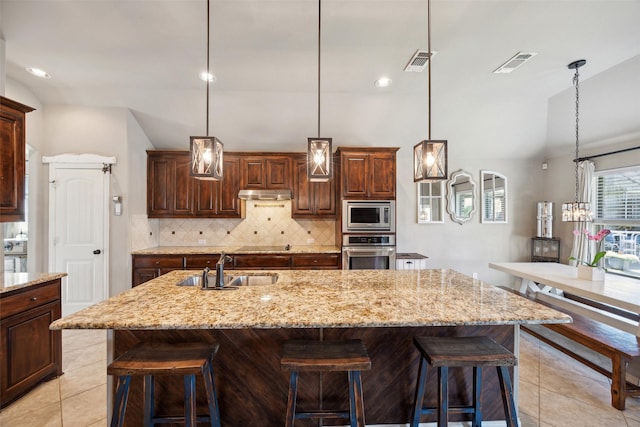 kitchen with stainless steel appliances, decorative backsplash, sink, and a spacious island