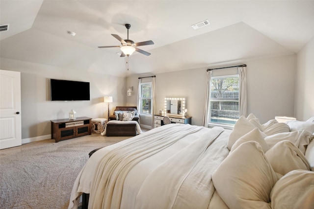 carpeted bedroom with vaulted ceiling, ceiling fan, and a tray ceiling