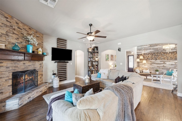 living room featuring ceiling fan, dark hardwood / wood-style floors, wood walls, and a fireplace