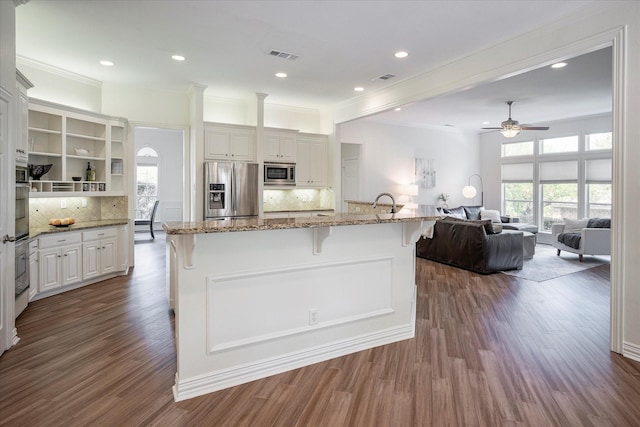 kitchen with light stone counters, ceiling fan, a breakfast bar area, dark hardwood / wood-style flooring, and appliances with stainless steel finishes