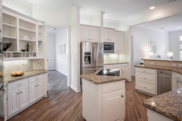 kitchen featuring appliances with stainless steel finishes, white cabinetry, a center island, and tasteful backsplash