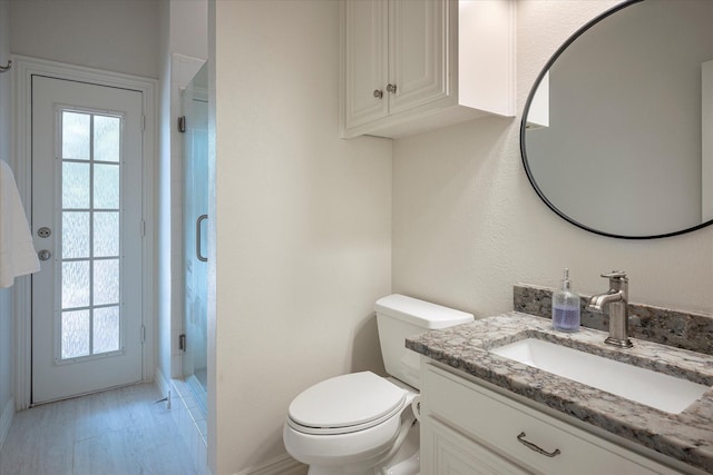 bathroom featuring an enclosed shower, vanity, and toilet