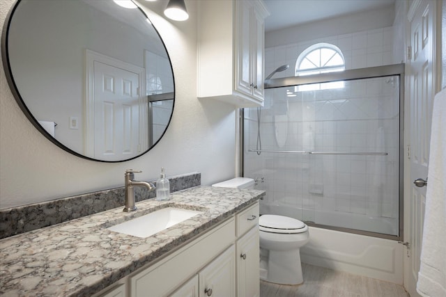 full bathroom featuring toilet, vanity, and combined bath / shower with glass door